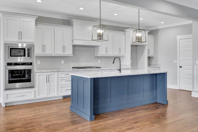 kitchen featuring ornamental molding, white cabinetry, stainless steel appliances, and wood finished floors