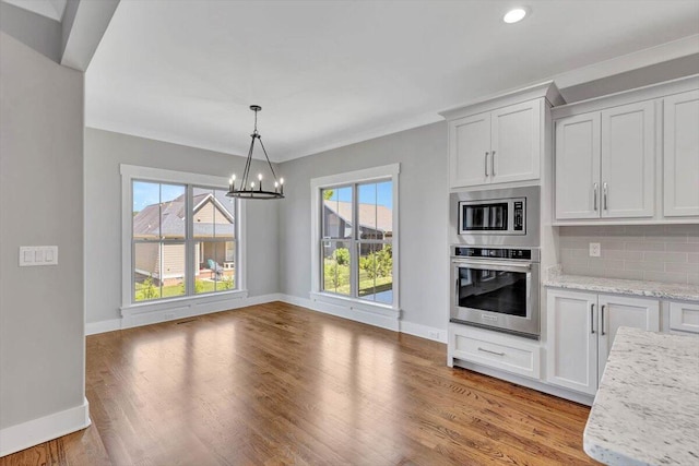 kitchen featuring white cabinetry, stainless steel appliances, an inviting chandelier, light stone countertops, and light hardwood / wood-style floors