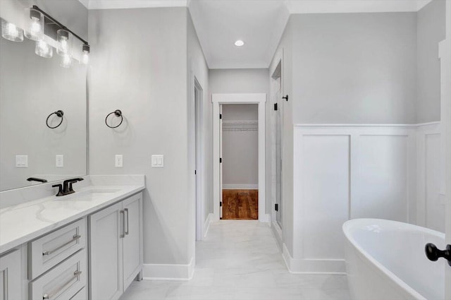 bathroom with vanity, a wainscoted wall, a freestanding bath, a walk in closet, and marble finish floor