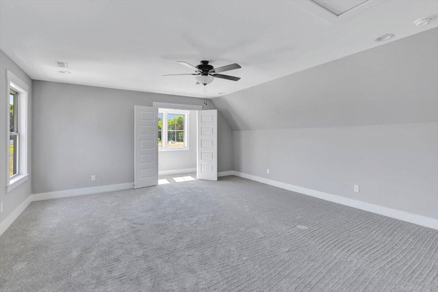 additional living space featuring visible vents, a ceiling fan, carpet flooring, baseboards, and vaulted ceiling