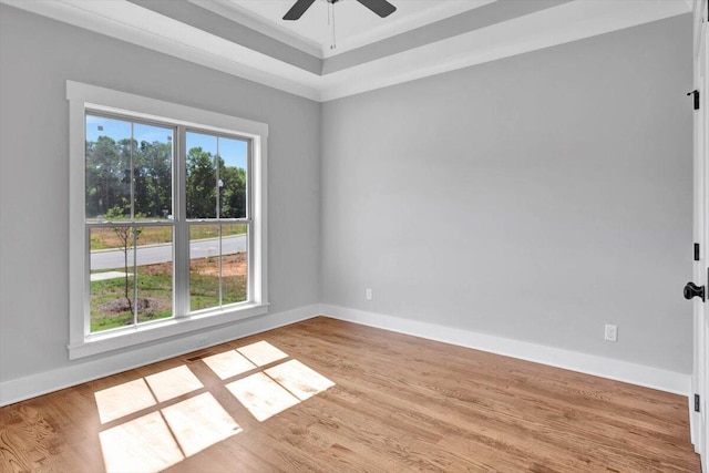 spare room with a wealth of natural light, baseboards, wood finished floors, and a ceiling fan