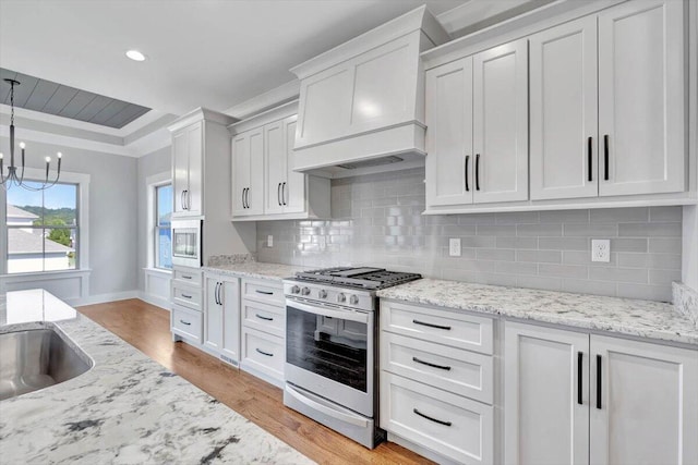 kitchen featuring custom exhaust hood, tasteful backsplash, appliances with stainless steel finishes, white cabinetry, and pendant lighting