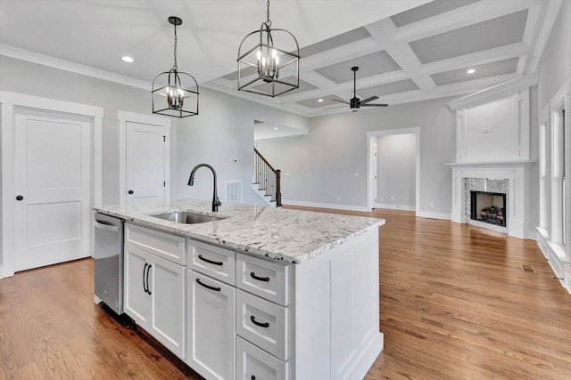 kitchen featuring sink, light wood-type flooring, an island with sink, stainless steel dishwasher, and white cabinets