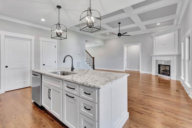 kitchen featuring a sink, stainless steel dishwasher, wood finished floors, white cabinets, and a premium fireplace