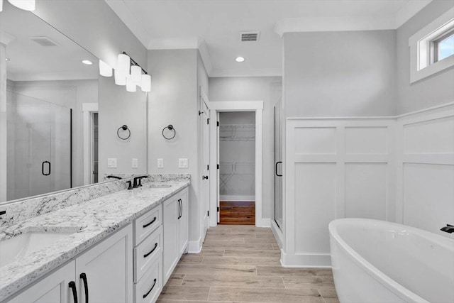 bathroom with vanity, crown molding, wood-type flooring, and plus walk in shower