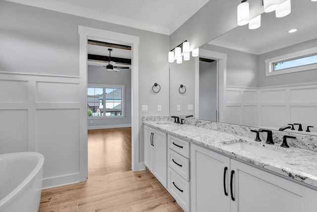 bathroom with a tub, ceiling fan, vanity, hardwood / wood-style flooring, and ornamental molding