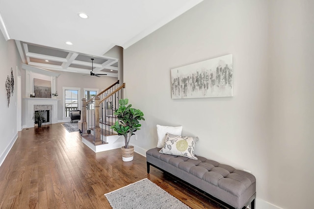 living area with coffered ceiling, wood finished floors, stairway, a fireplace, and baseboards