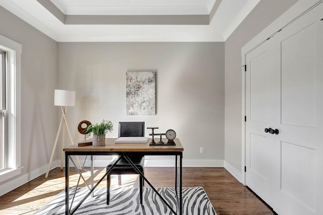 office area with a raised ceiling, wood finished floors, baseboards, and ornamental molding