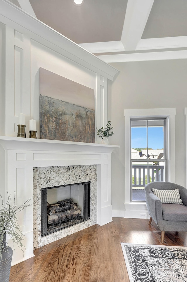 living area featuring beamed ceiling, a fireplace, and wood finished floors