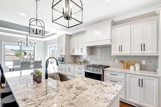 kitchen with decorative backsplash, stainless steel appliances, white cabinetry, wall chimney exhaust hood, and a sink