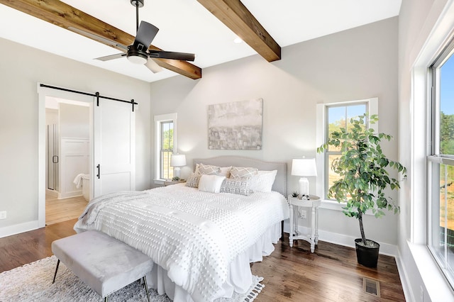 bedroom with beam ceiling, a barn door, dark hardwood / wood-style floors, and ceiling fan