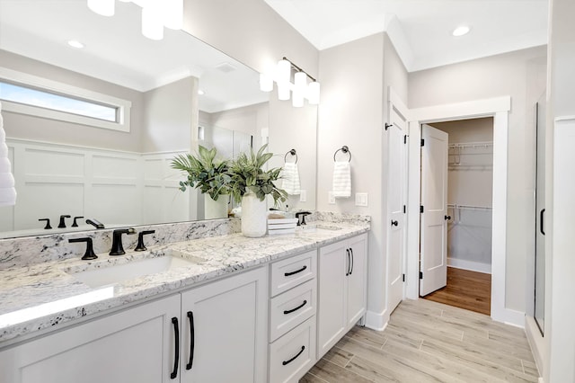 bathroom with vanity, ornamental molding, a shower with shower door, and wood-type flooring