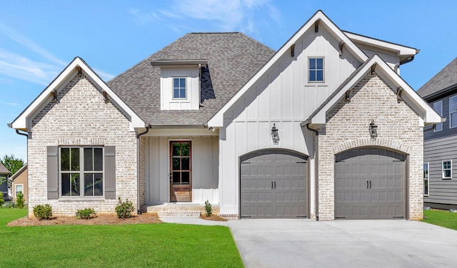 view of front of house featuring driveway, a shingled roof, a front lawn, board and batten siding, and brick siding