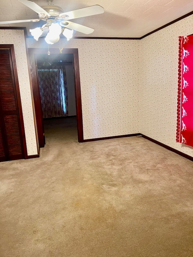 empty room featuring crown molding, ceiling fan, and carpet flooring