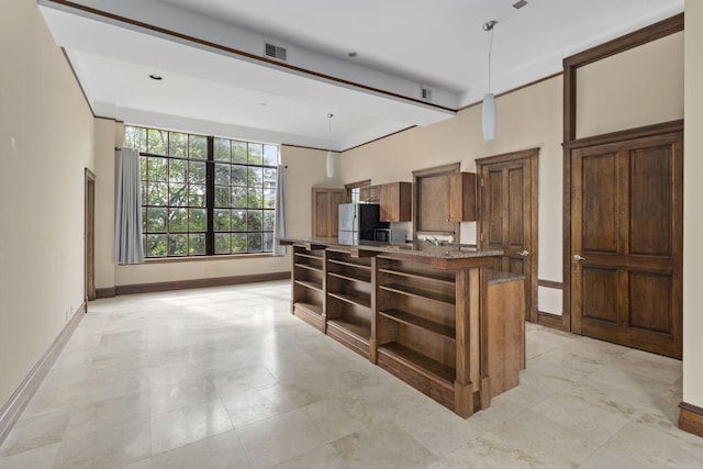 kitchen with pendant lighting, dark stone countertops, and stainless steel fridge