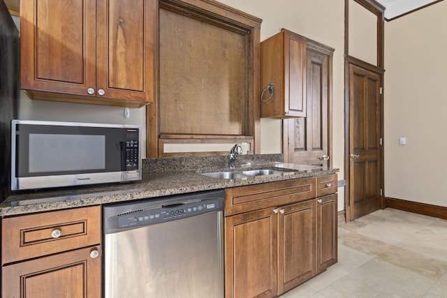 kitchen with stainless steel appliances, sink, and dark stone countertops