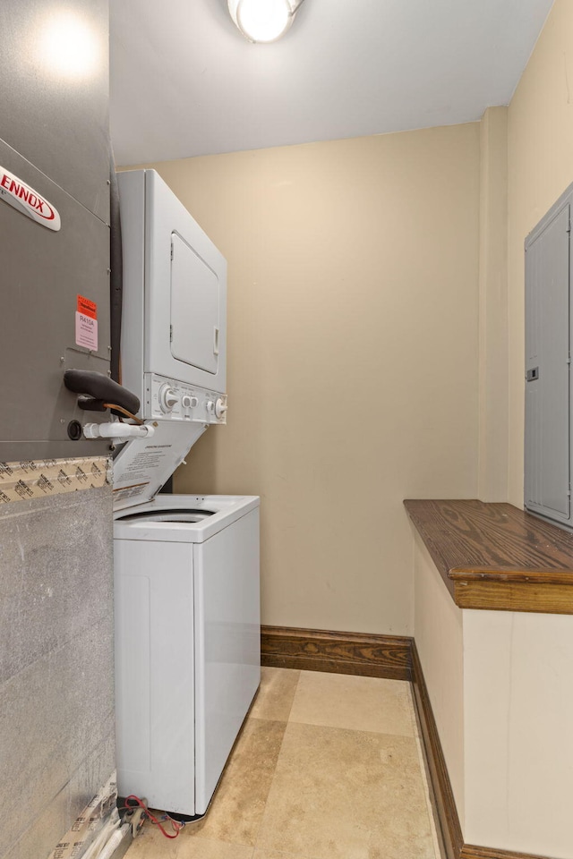 laundry room featuring electric panel and stacked washer / dryer