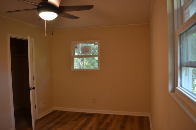 unfurnished bedroom featuring dark wood-type flooring, a spacious closet, ceiling fan, and a closet