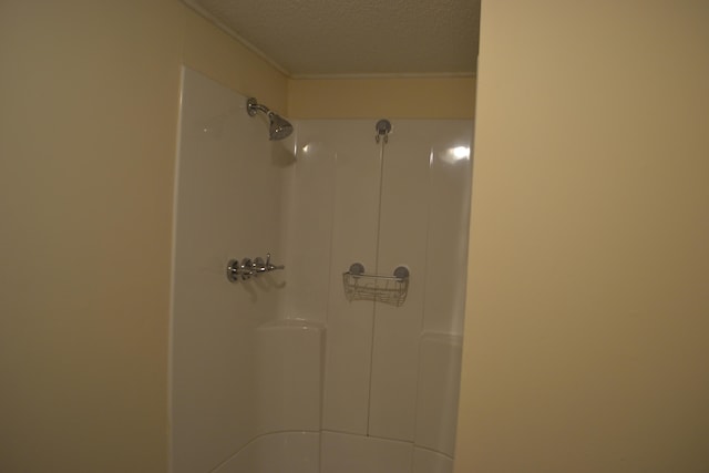 interior details with ornamental molding, a textured ceiling, and a shower