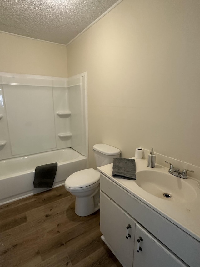 bathroom with a textured ceiling, shower / tub combination, toilet, wood finished floors, and vanity