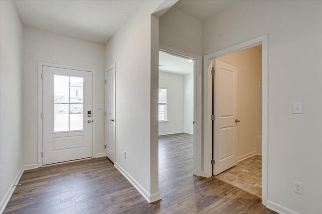 doorway to outside featuring dark wood-type flooring, a textured ceiling, and a healthy amount of sunlight