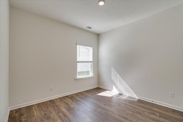 spare room with a textured ceiling and dark wood-type flooring