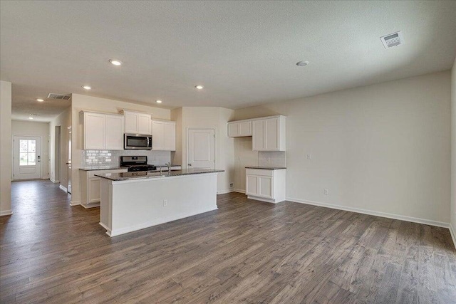 kitchen featuring appliances with stainless steel finishes, dark hardwood / wood-style flooring, white cabinetry, an island with sink, and a textured ceiling