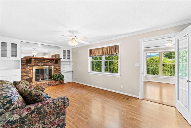 living room featuring ornamental molding, a brick fireplace, ceiling fan, and light hardwood / wood-style floors