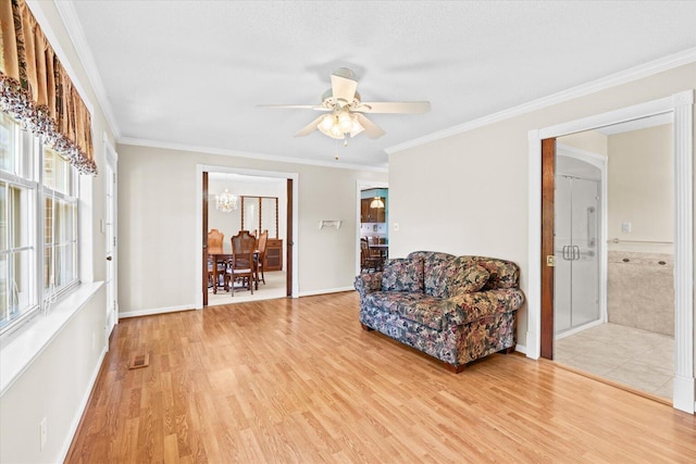 living area with ceiling fan, a textured ceiling, crown molding, and light hardwood / wood-style flooring