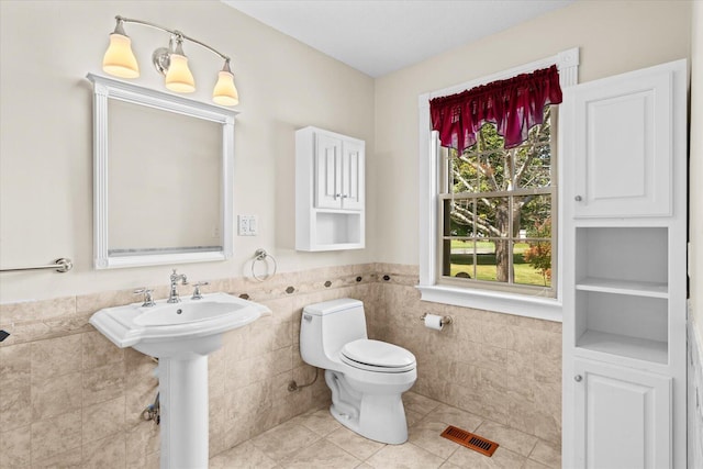 bathroom featuring tile walls, tile patterned flooring, and toilet