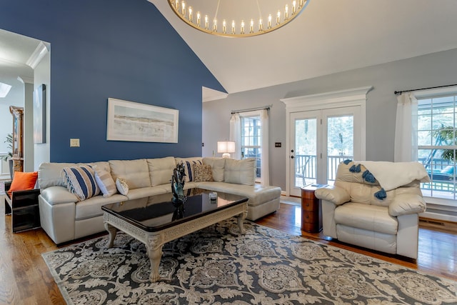 living room with a chandelier, wood-type flooring, and vaulted ceiling