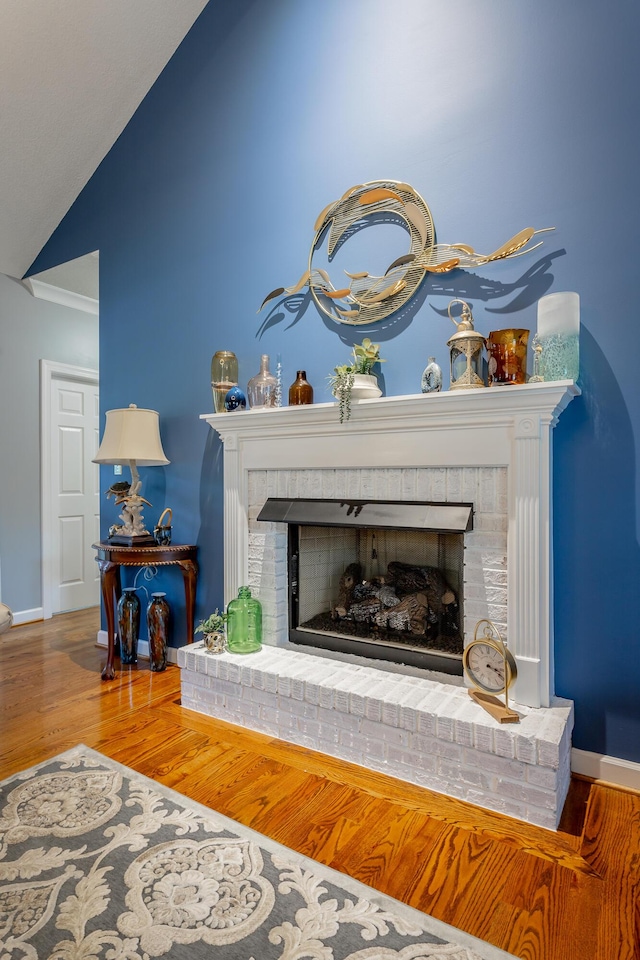 interior details featuring hardwood / wood-style flooring, crown molding, and a brick fireplace