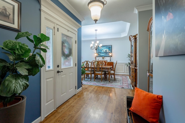 entrance foyer with crown molding, light hardwood / wood-style flooring, and a chandelier