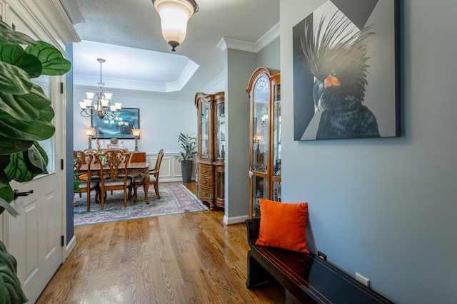 corridor featuring a textured ceiling, hardwood / wood-style flooring, a notable chandelier, and ornamental molding