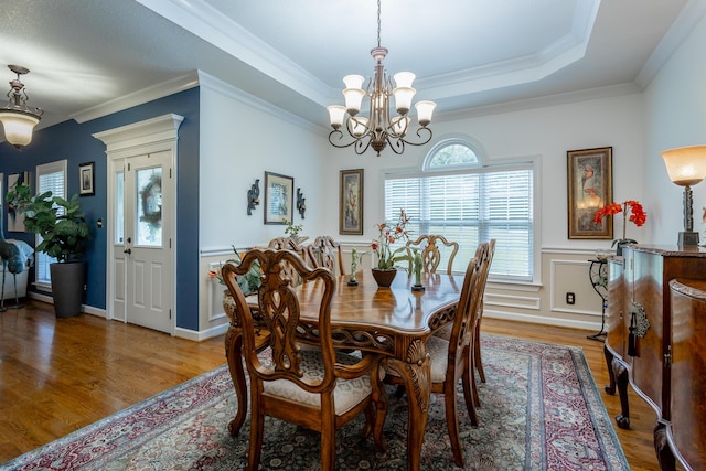 dining space featuring hardwood / wood-style floors, ornamental molding, a tray ceiling, and a chandelier