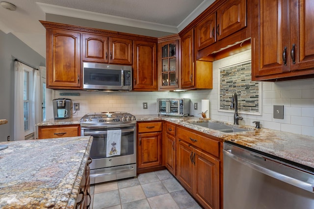 kitchen featuring backsplash, light stone counters, sink, and stainless steel appliances