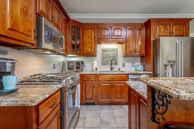 kitchen featuring light stone counters, sink, stainless steel appliances, and tasteful backsplash