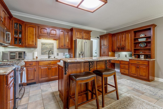 kitchen with sink, tasteful backsplash, crown molding, a kitchen island, and appliances with stainless steel finishes