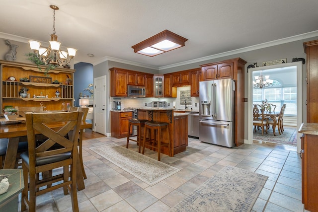 kitchen with a center island, an inviting chandelier, crown molding, a breakfast bar area, and stainless steel appliances