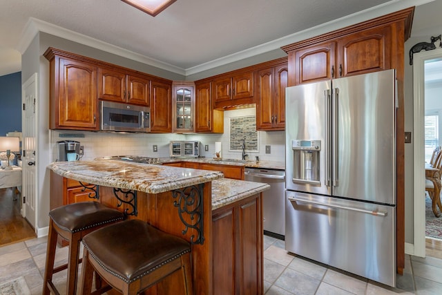 kitchen with light stone countertops, appliances with stainless steel finishes, decorative backsplash, a kitchen island, and a breakfast bar area