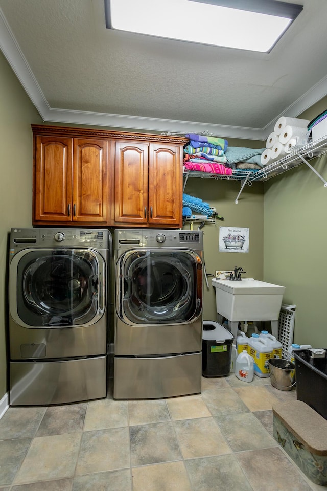 clothes washing area with cabinets, sink, crown molding, and washing machine and clothes dryer