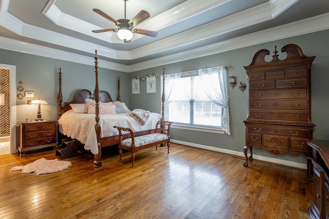 bedroom featuring hardwood / wood-style flooring, ceiling fan, ornamental molding, and a tray ceiling