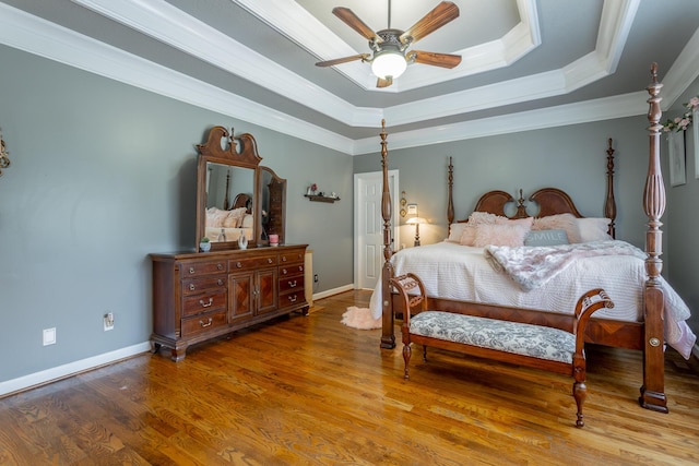 bedroom featuring a raised ceiling, ceiling fan, hardwood / wood-style flooring, and ornamental molding