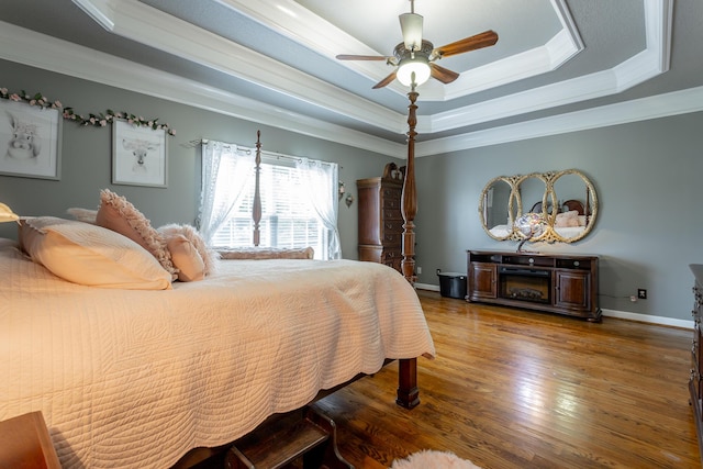 bedroom featuring a raised ceiling, ceiling fan, hardwood / wood-style floors, and ornamental molding