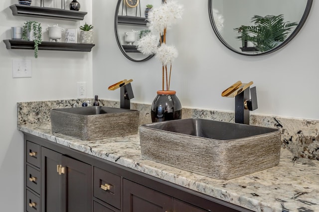 kitchen with dark brown cabinets, light stone counters, and sink