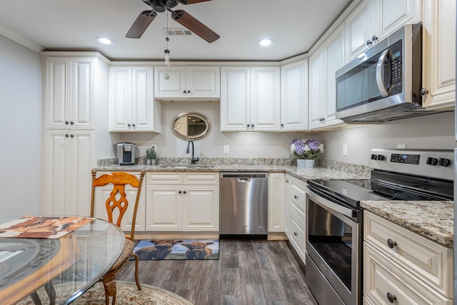 kitchen with white cabinets, sink, dark hardwood / wood-style floors, light stone counters, and stainless steel appliances