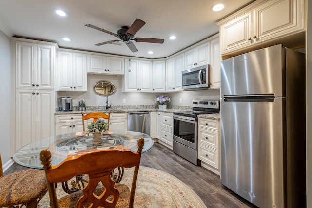 kitchen with ceiling fan, light stone counters, dark hardwood / wood-style floors, white cabinets, and appliances with stainless steel finishes