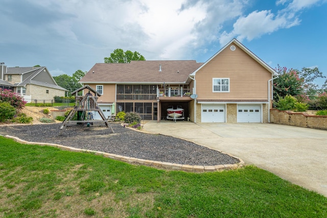 back of property with a yard, a garage, and a sunroom