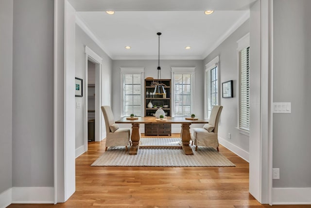 dining space with ornamental molding and light wood-type flooring