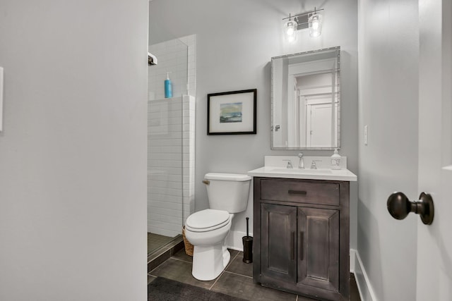 bathroom featuring vanity, toilet, a tile shower, and tile patterned floors